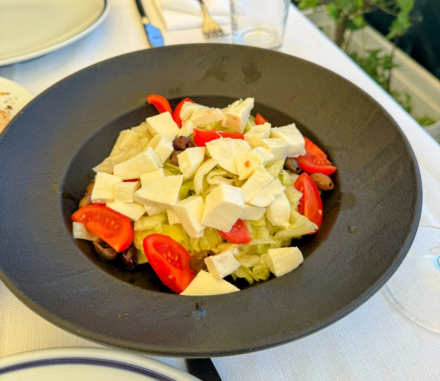 Insalata con lattuga, pomodoro e mozzarella in una ciotola nera, fotografata a L’Ascensore