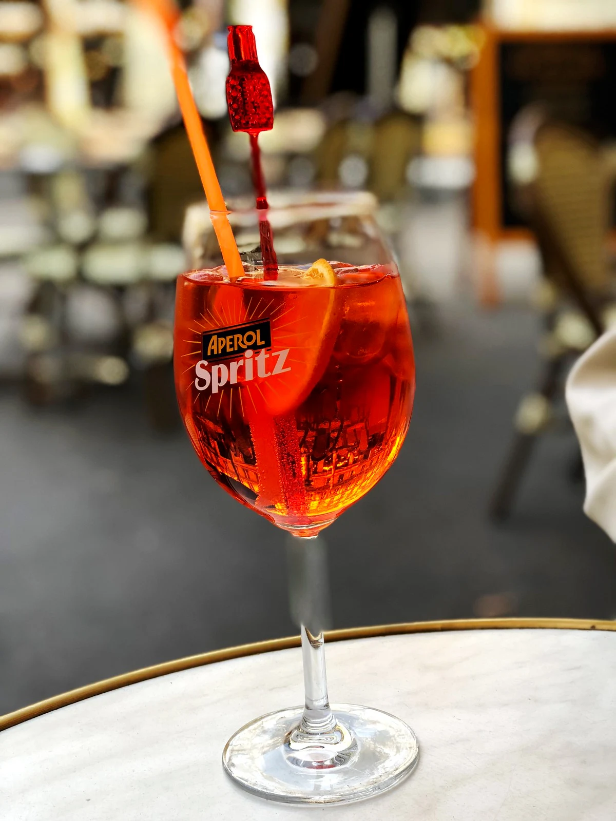 Aperol Spritz con ghiaccio e fetta d’arancia in un calice su un tavolino da caffè